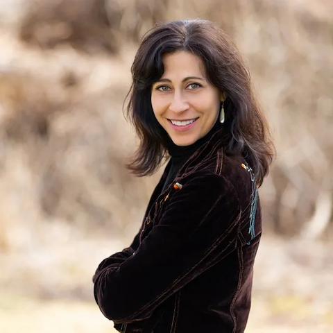 Ana Guigui outdoors looking at the camera and smiling in a black sweater
