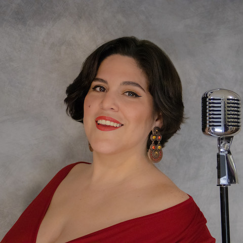 Gaby Cotter in a red dress next to a vintage microphone