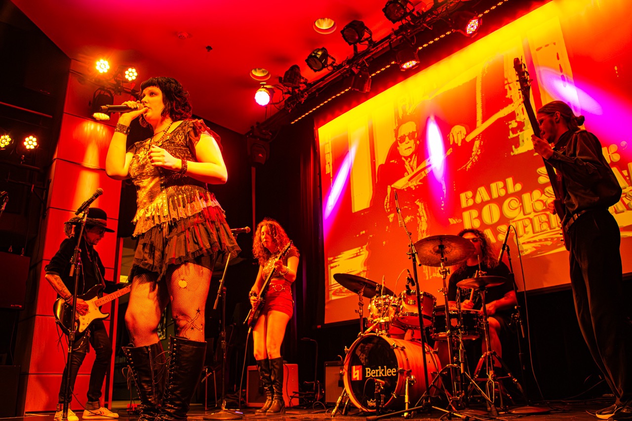 Performers on stage shot from a low angle with red lighting