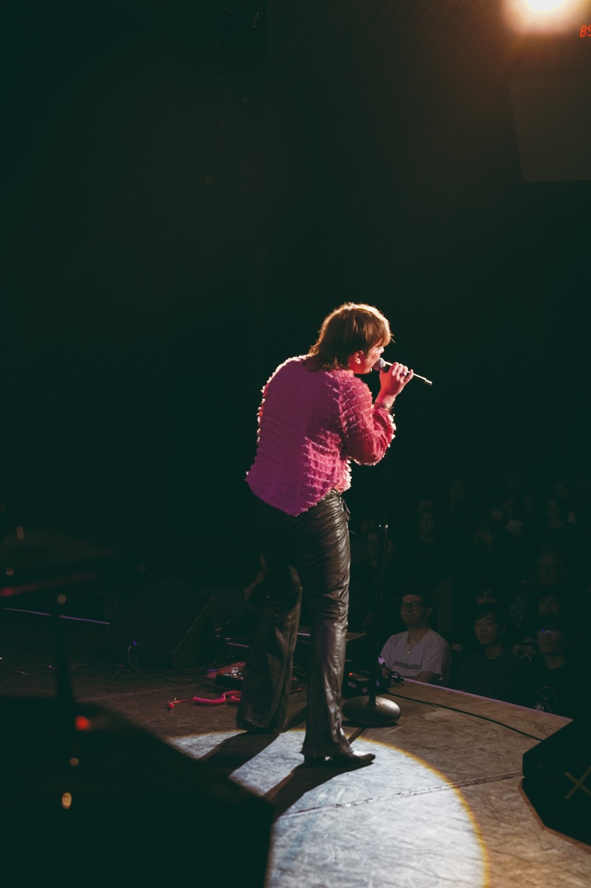 student singing on stage shot from behind in a spotlight
