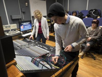 Person organizing wires on a large mixing board