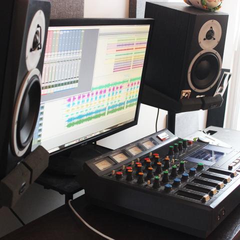 Home studio set up with mixing console, monitor, and speakers on either side