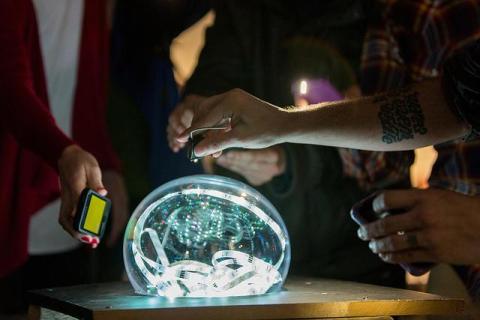 A picture of someone holding a phone to a brain model. 