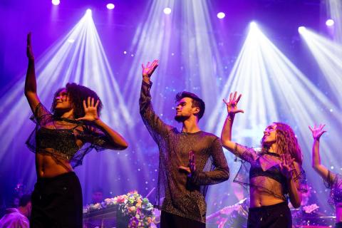 Students dancing on stage for the Coldplay Signature Series show with lots of spotlights in the background